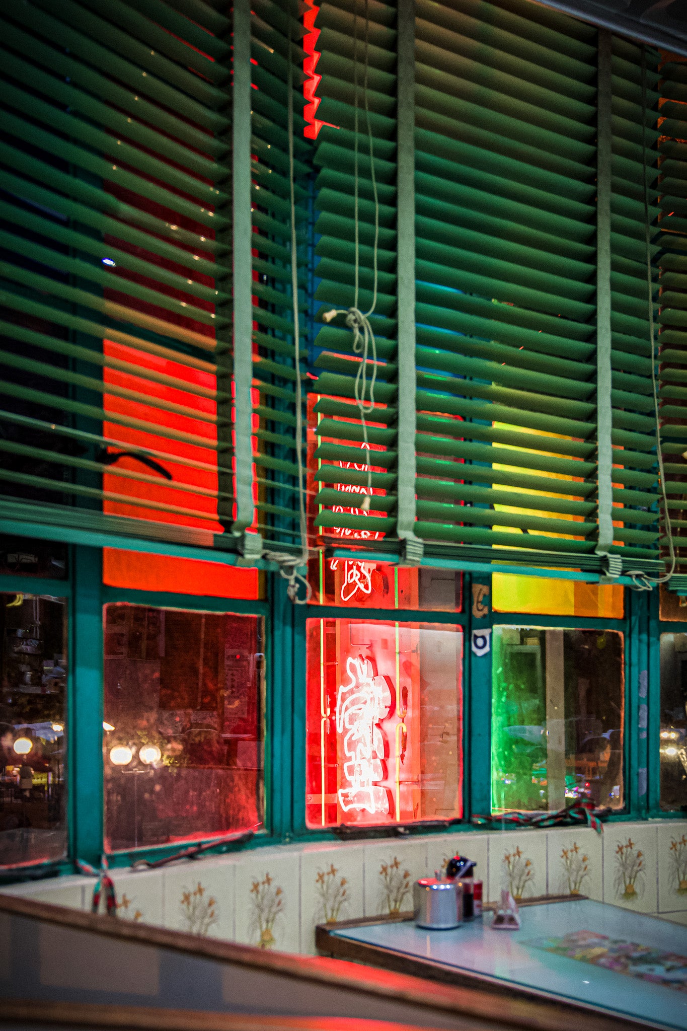 A chromoluxe gloss metal print featuring a colorful neon sign in a window, with a blurred background. Shot in the infamous Mido Cafe in Yau Ma Tei