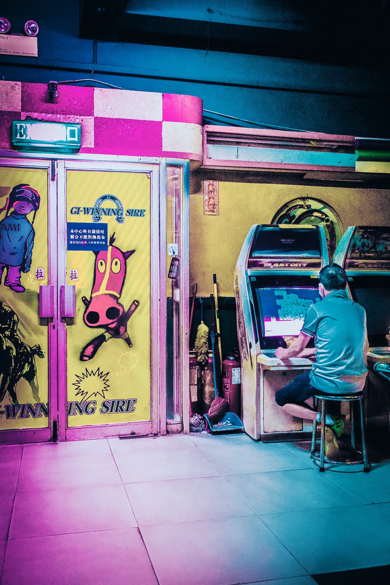 a man sat at an arcade machine found in the many traditional arcade machines of Hong Kong