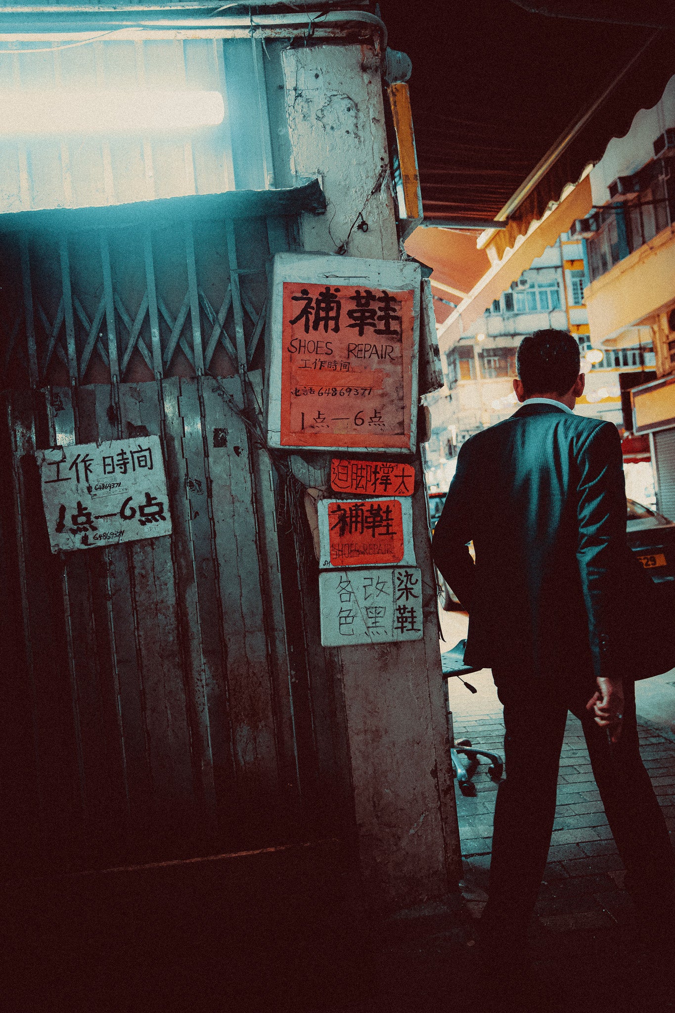 A metal print of a sharply dressed man walking past traditional signage in an alleyway, capturing a cinematic vibe of Hong Kong.