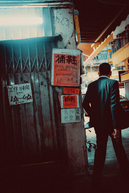 A metal print of a sharply dressed man walking past traditional signage in an alleyway, capturing a cinematic vibe of Hong Kong.