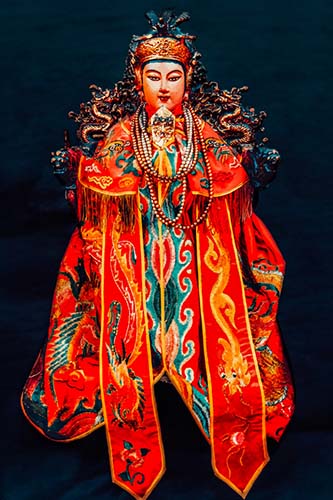 A colorful artwork featuring an god like character with a red and green costume and a golden halo, placed on a wooden frame.