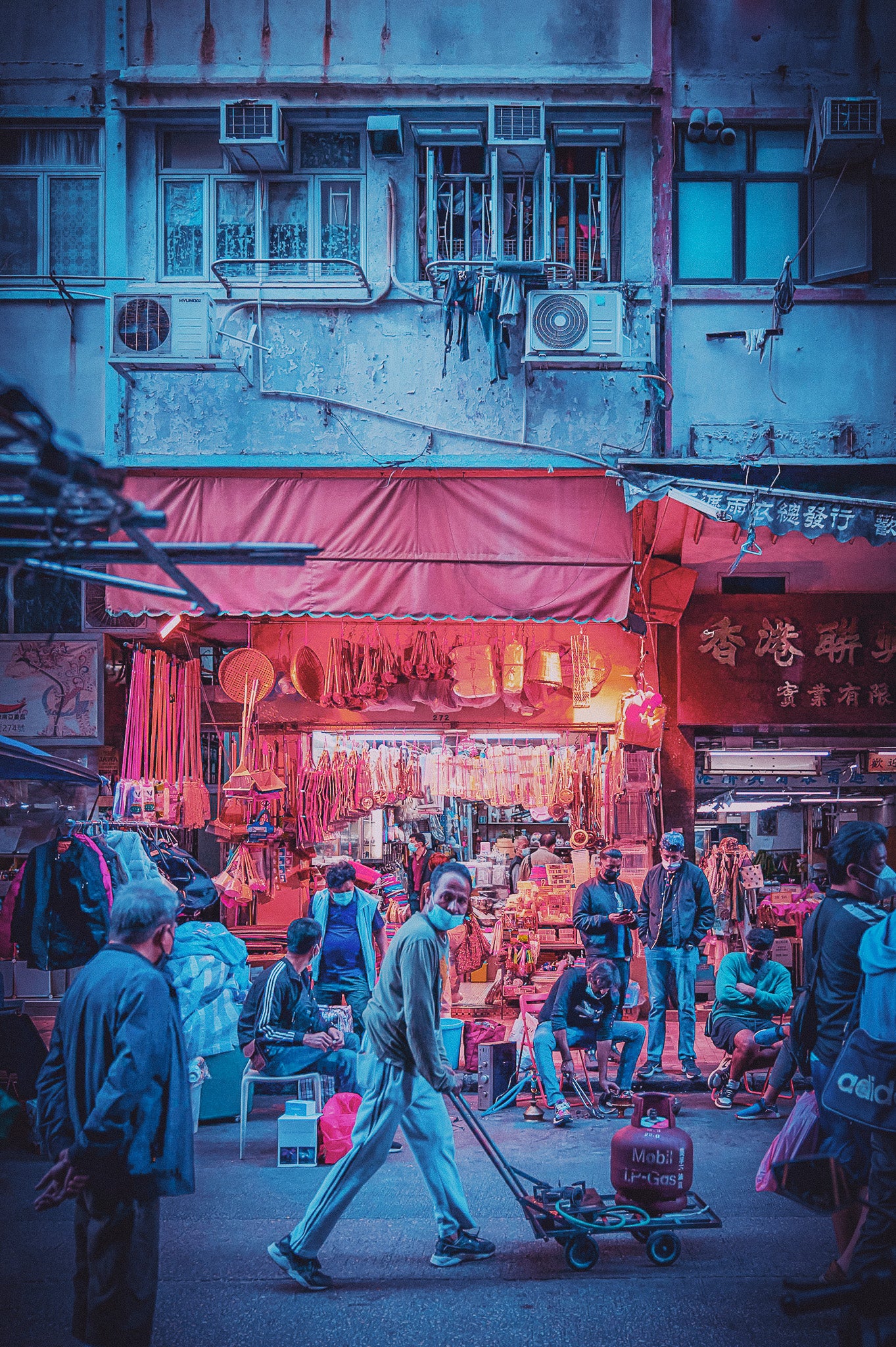 A black and white image of a bustling city street at night, with people walking and various shops along the way, including a dim sum restaurant.