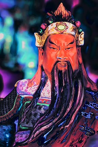 A colorful artwork depicting the figure of Guan Di, the Chinese god of war, with a detailed and vibrant design, housed in a wooden frame.