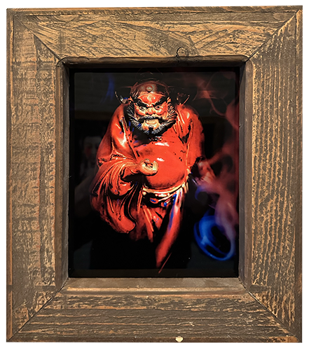 A framed chromoluxe gloss metal print featuring a stylized illustration of a mythological character in red and black attire, with a wooden frame.